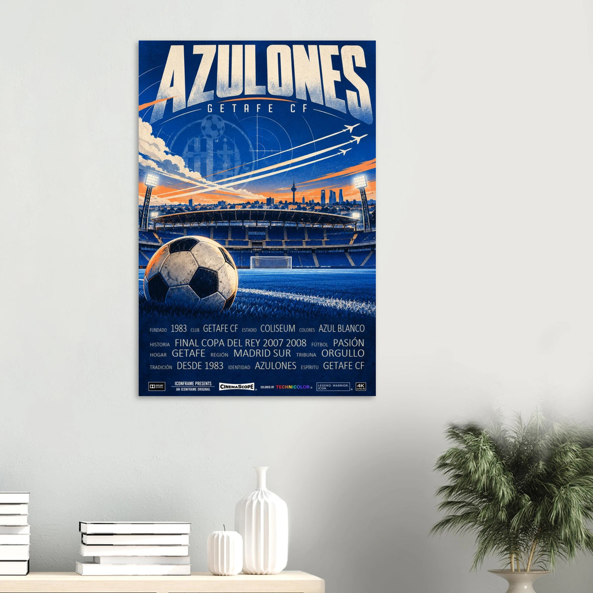 Getafe Poster „Azulones“ an einer hellen Wand über einem Tisch mit Büchern und Vasen