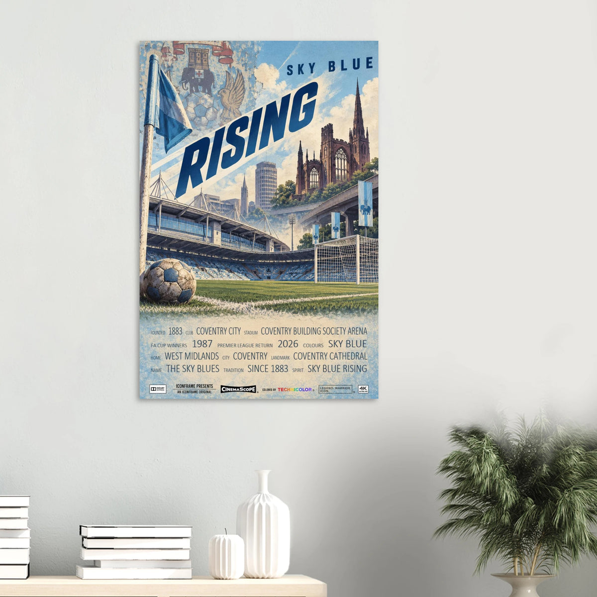 Coventry City Poster „Sky Blue Rising“ an einer hellen Wand über Büchern und weißen Vasen