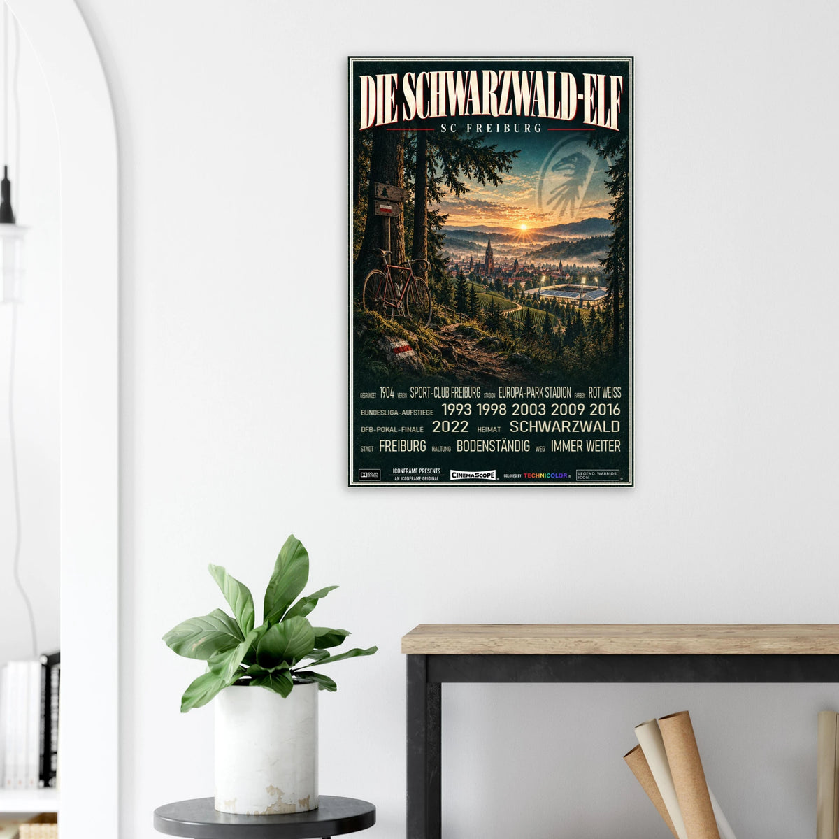 SC Freiburg Poster „Die Schwarzwald-Elf“ an einer hellen Wand neben einer Pflanze und einem Tisch
