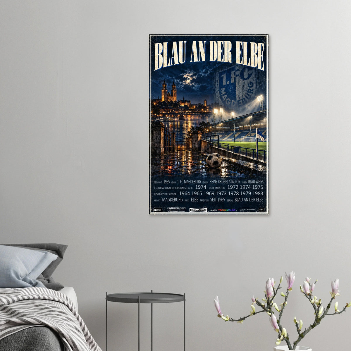 1. FC Magdeburg Poster „Blau an der Elbe“ an einer grauen Wand neben einem Bett
