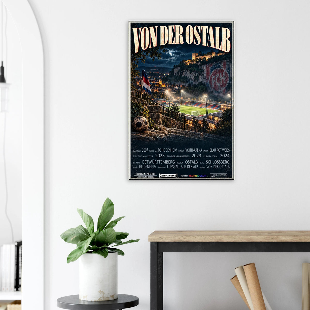 1. FC Heidenheim Poster „Von der Ostalb“ an einer hellen Wand neben einer Pflanze und einem Tisch