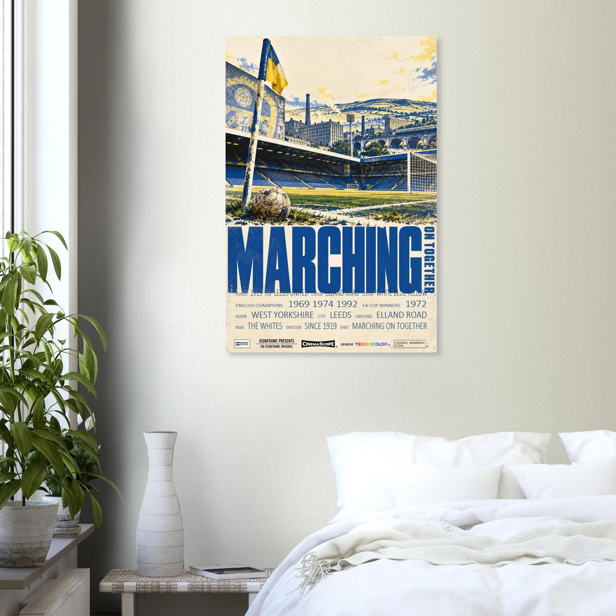 Leeds United Poster „Marching on Together“ an einer hellen Wand neben einem weiß bezogenen Bett