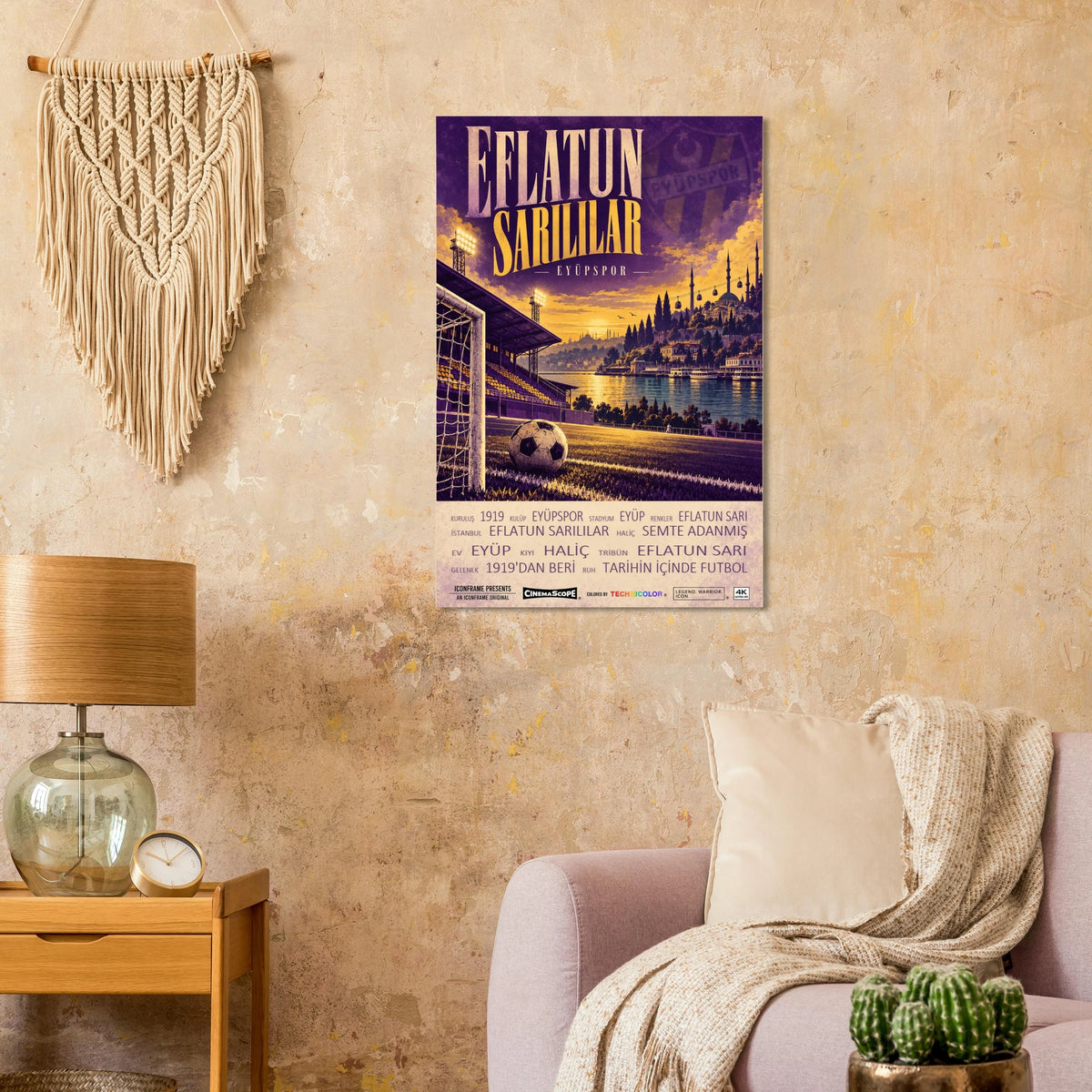Eyüpspor Poster „Eflatun Sarılılar“ an einer beigen Wand neben einem Sessel und einer Tischlampe