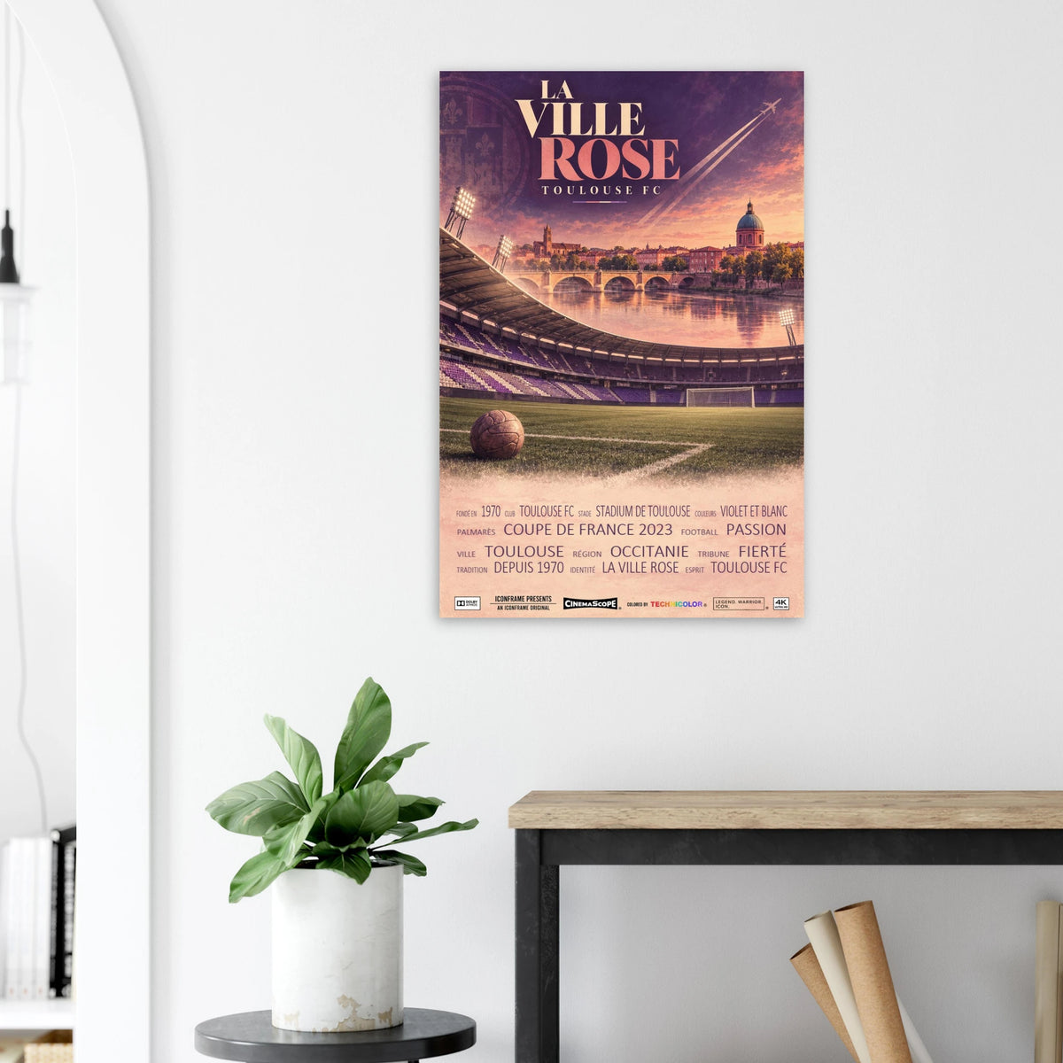 FC Toulouse Poster „La Ville Rose“ an einer hellen Wand neben einer Pflanze und einem Tisch