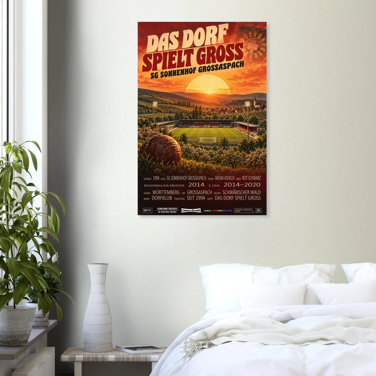 Sonnenhof Großaspach Poster „Das Dorf spielt groß“ an einer hellen Wand über einem weiß bezogenen Bett