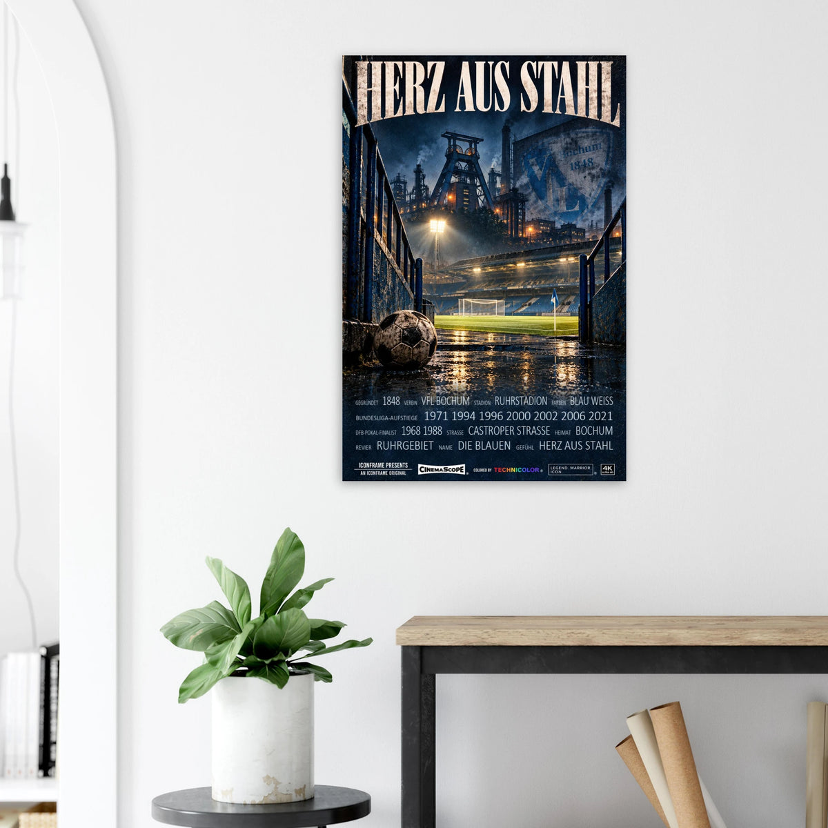 VfL Bochum Poster „Herz aus Stahl“ an einer hellen Wand neben einer Pflanze und einem Tisch