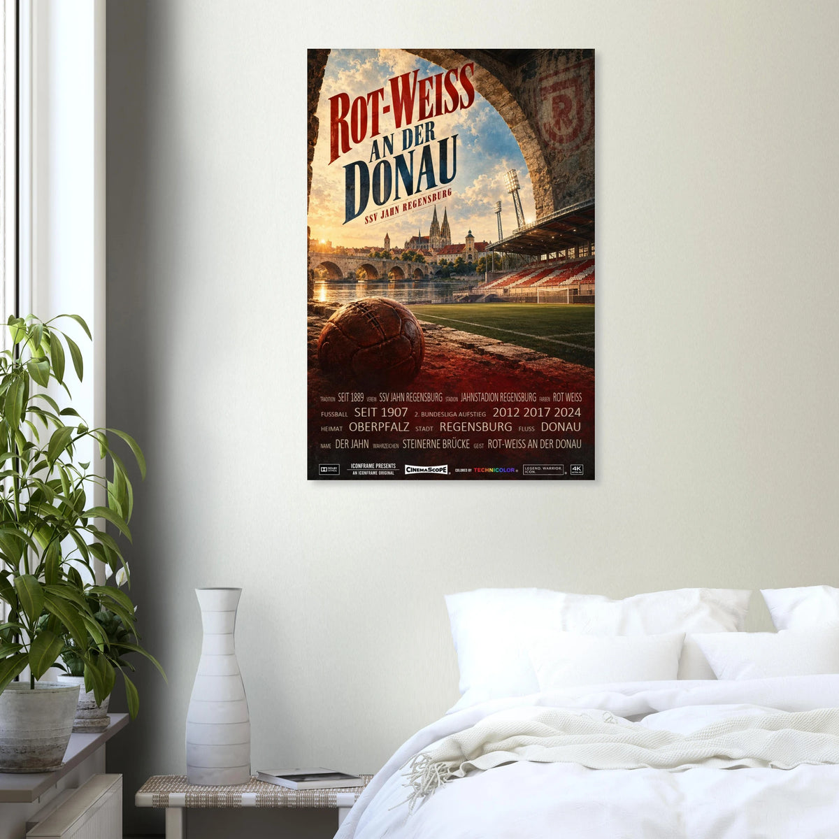 SSV Jahn Regensburg Poster „Rot-Weiss an der Donau“ an einer hellen Wand über einem weiß bezogenen Bett