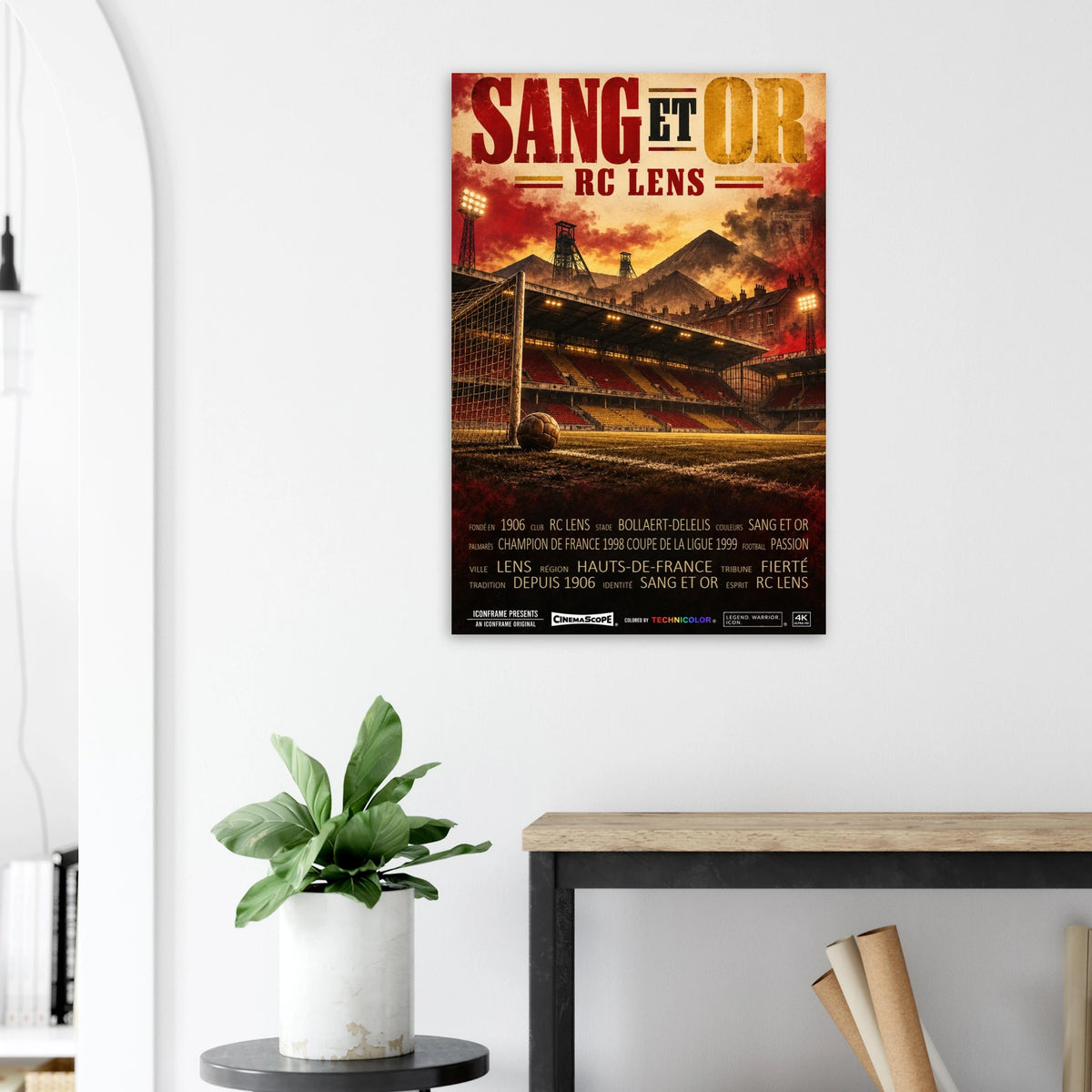 RC Lens Poster „Sang et Or“ an einer hellen Wand neben einer Pflanze und einem Tisch