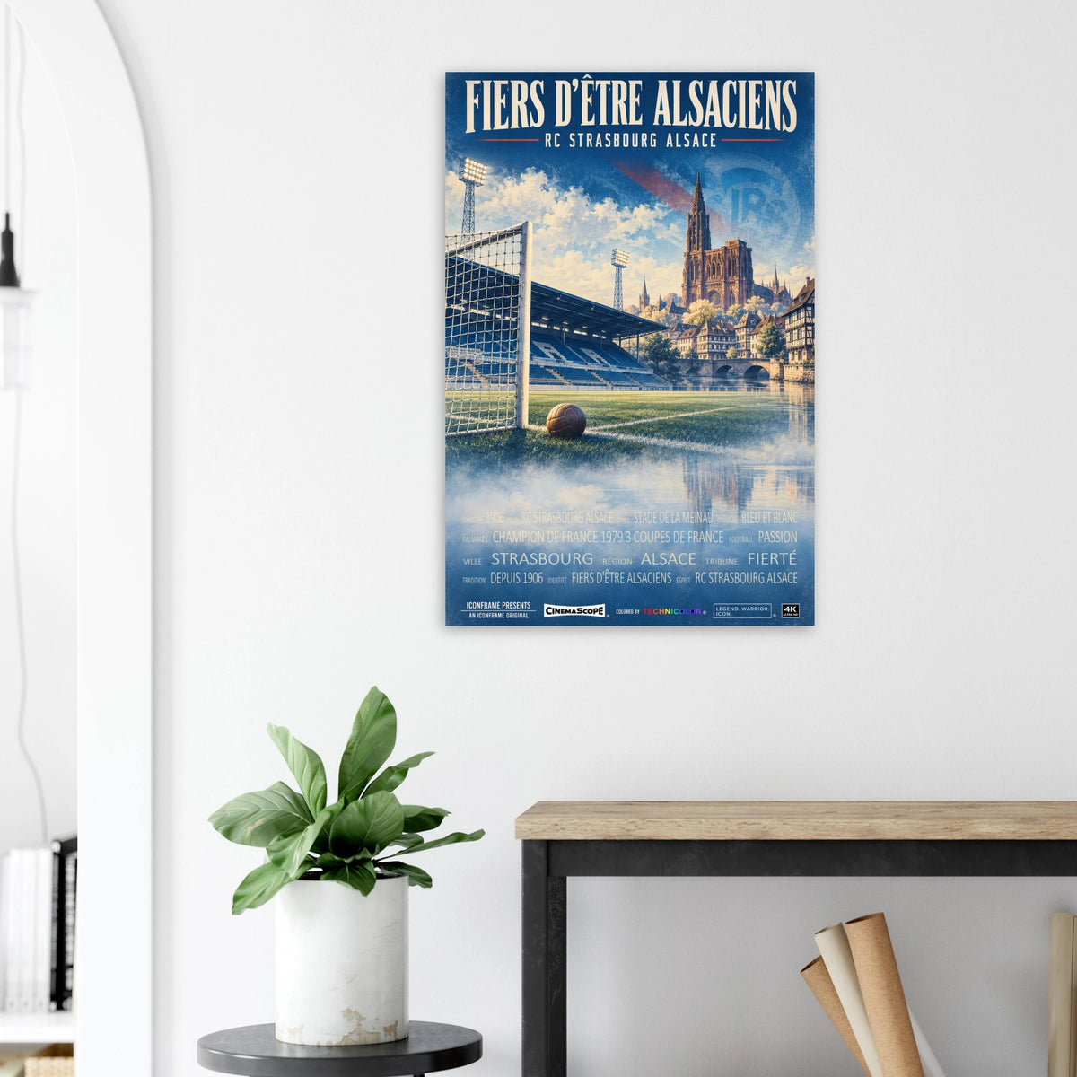 Racing Straßburg Poster „Fiers d’être Alsaciens“ an einer hellen Wand neben einer Pflanze und einem Tisch