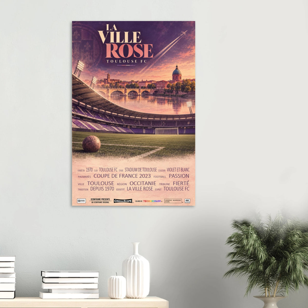 FC Toulouse Poster „La Ville Rose“ an einer hellen Wand über einer Ablage mit Büchern und Vasen
