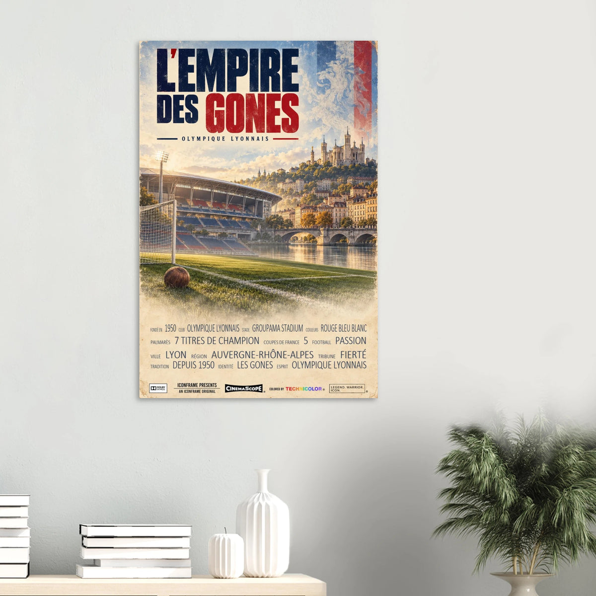 Olympique Lyon Poster „L’Empire des Gones“ an einer hellen Wand über einer Ablage mit Büchern und Vasen