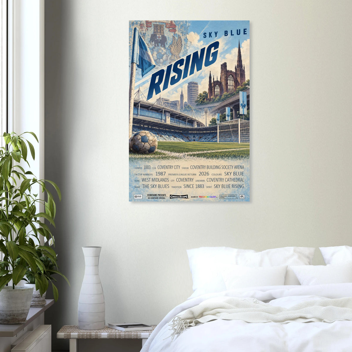 Coventry City Poster „Sky Blue Rising“ an einer hellen Wand neben einem weiß bezogenen Bett