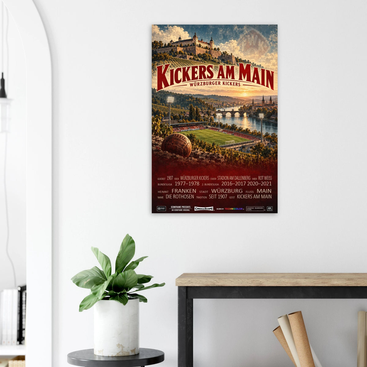Würzburger Kickers Poster „Kickers am Main“ an einer hellen Wand neben einer Pflanze und einem Tisch