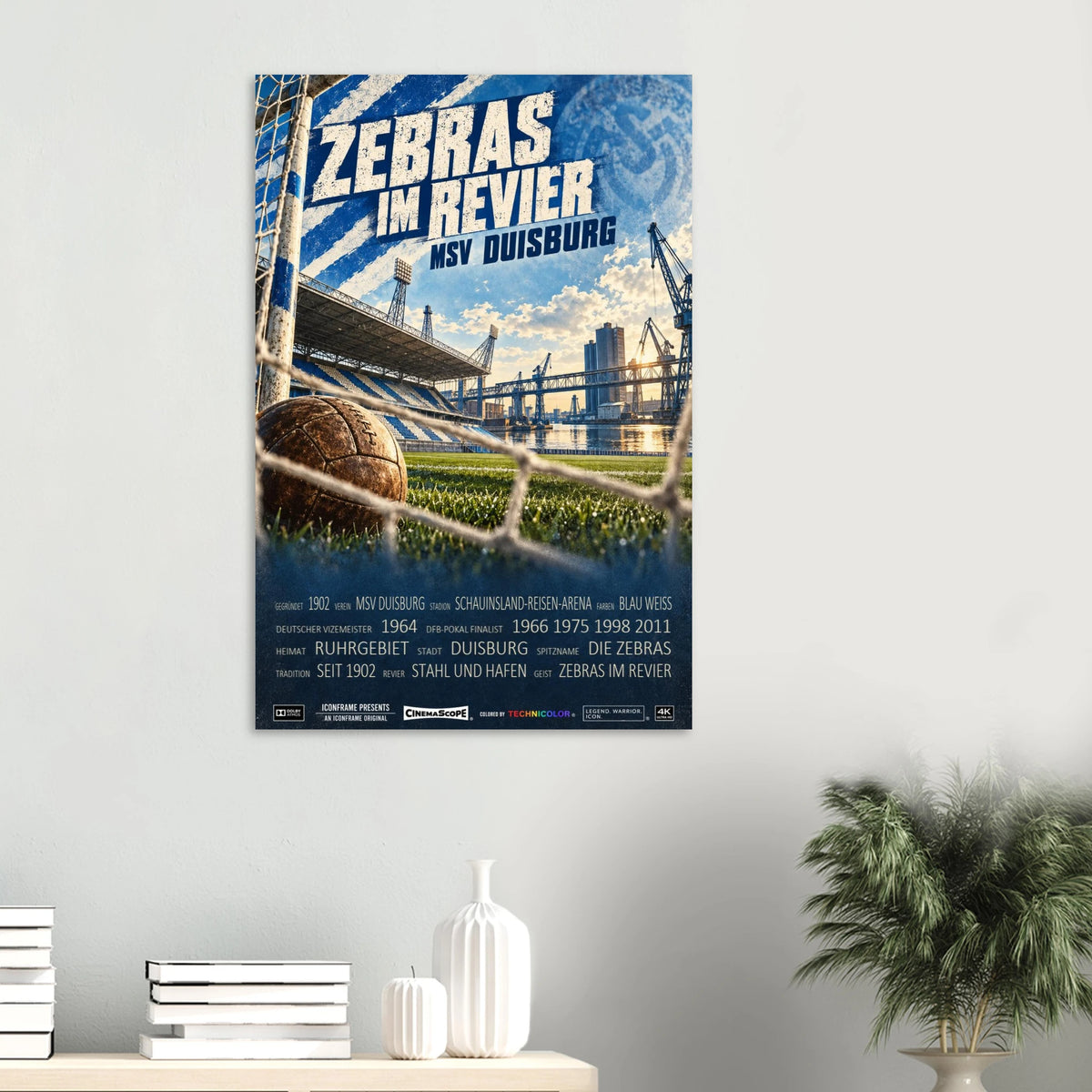 MSV Duisburg Poster „Zebras im Revier“ an einer hellen Wand über einer Ablage mit Büchern und Vasen