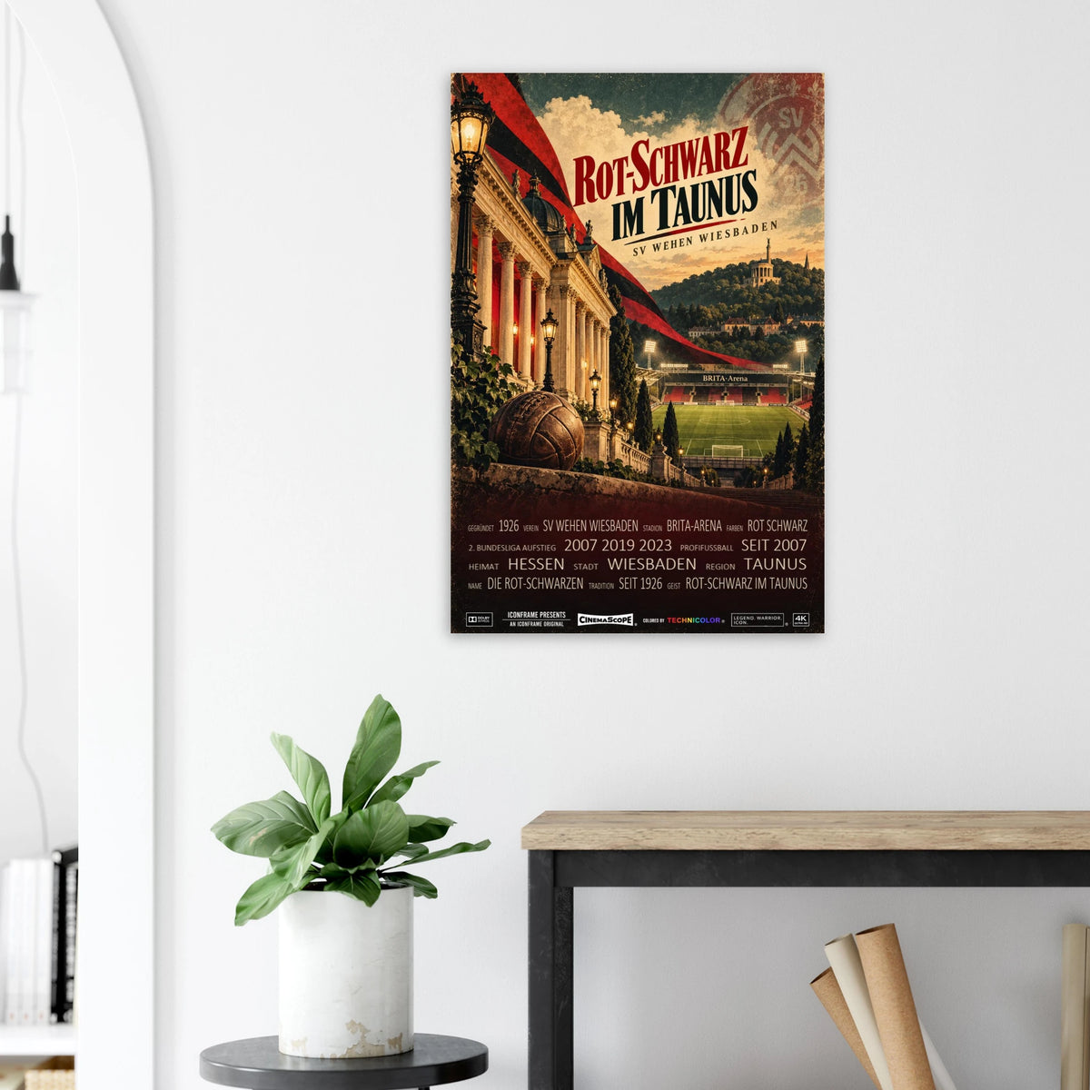 SV Wehen Wiesbaden Poster „Rot-Schwarz im Taunus“ an einer hellen Wand neben einer Pflanze und einem Tisch