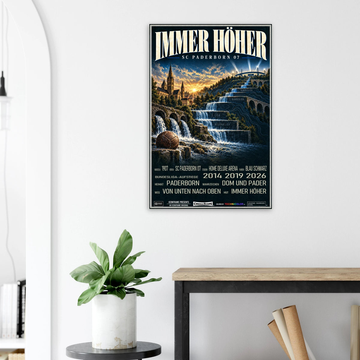 SC Paderborn 07 Poster „Immer höher“ an einer hellen Wand neben einer Pflanze und einem Tisch