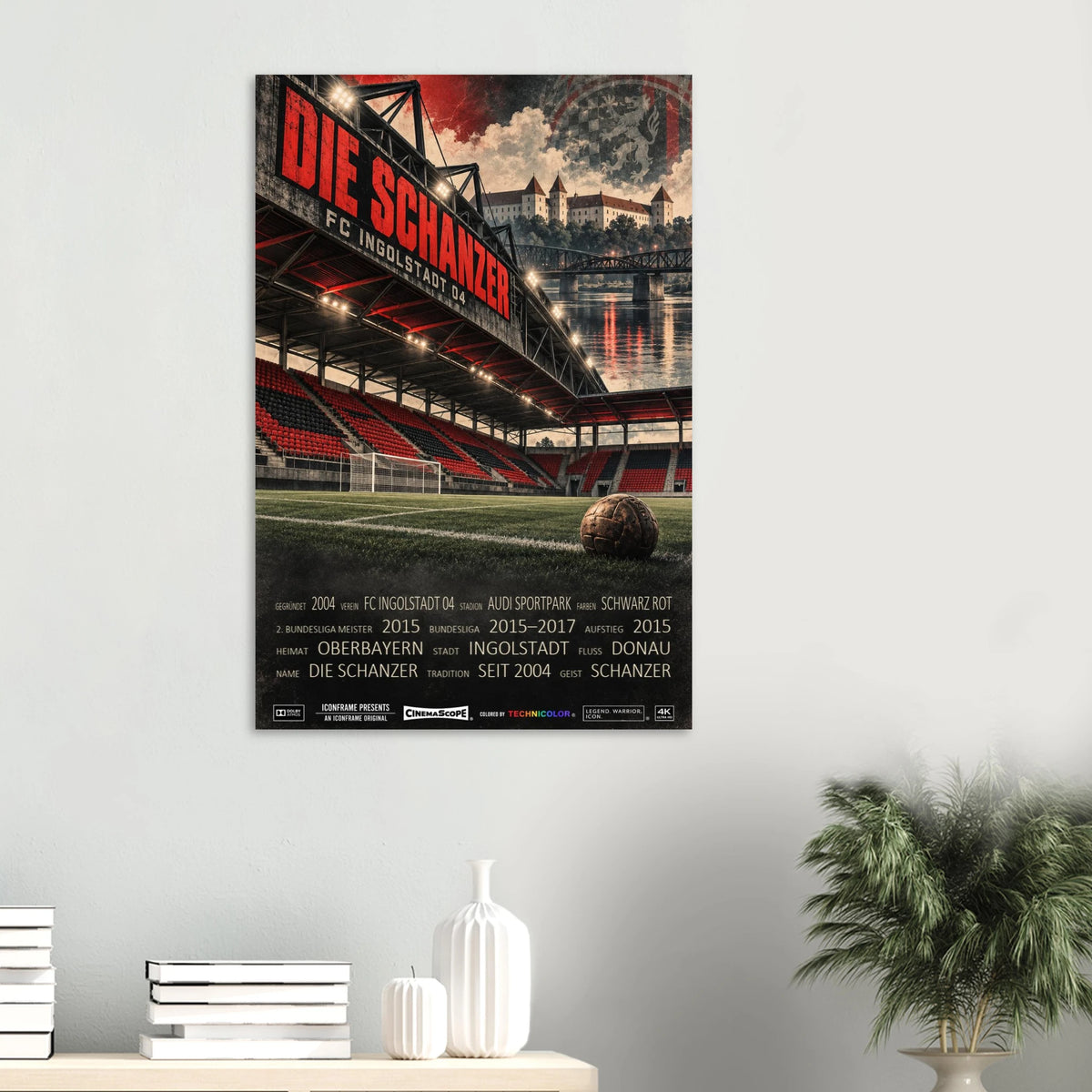 FC Ingolstadt 04 Poster „Die Schanzer“ an einer hellen Wand über einer Ablage mit Büchern und Vasen