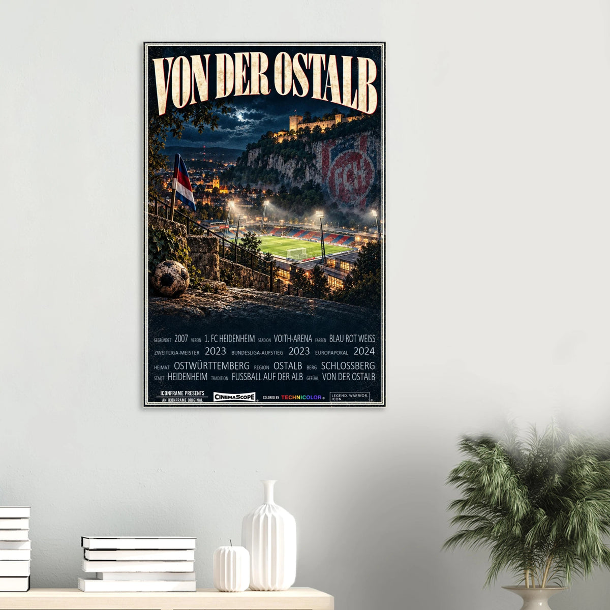1. FC Heidenheim Poster „Von der Ostalb“ an einer hellen Wand über Büchern und weißen Vasen
