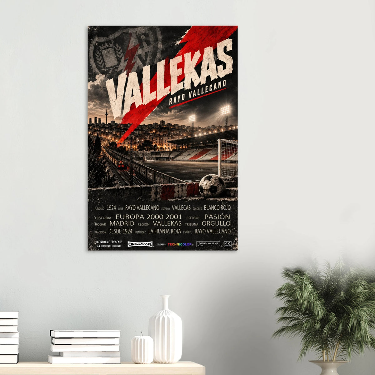 Rayo Vallecano Poster „Vallekas“ an einer hellen Wand über einem Tisch mit Büchern und Vasen