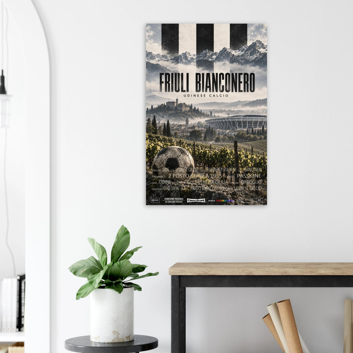 Udinese Calcio Poster „Friuli Bianconero“ an einer hellen Wand neben einer Pflanze und einem Tisch