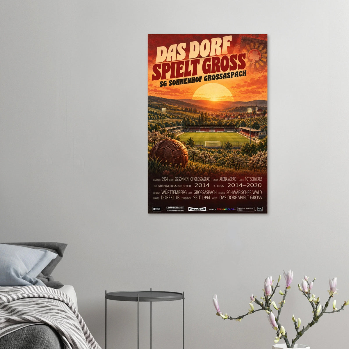 Sonnenhof Großaspach Poster „Das Dorf spielt groß“ an einer grauen Wand neben einem Bett